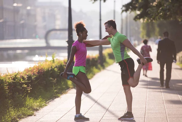 Trotar pareja calentamiento y estiramiento en la ciudad —  Fotos de Stock