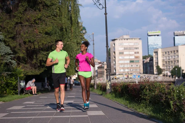 Jeune souriant couple multiethnique jogging dans la ville — Photo