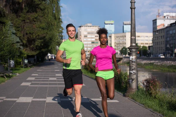 Jeune souriant couple multiethnique jogging dans la ville — Photo