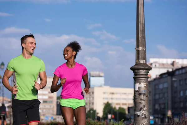 Joven sonriente pareja multiétnica trotando en la ciudad — Foto de Stock