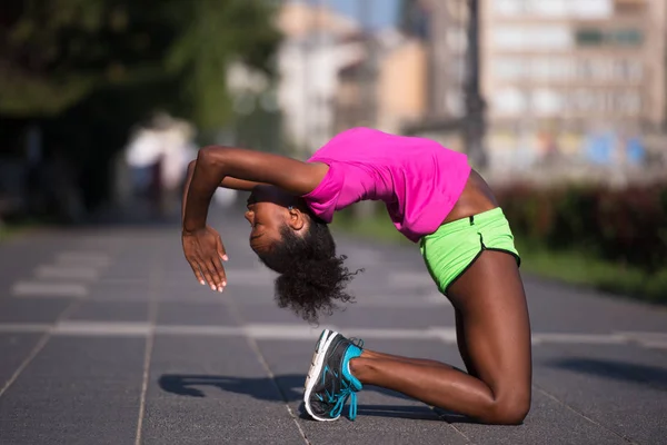 Спортивная молодая африканская американка, растянувшаяся на открытом воздухе — стоковое фото