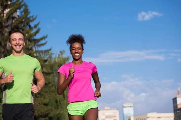 Muda tersenyum pasangan multietnis joging di kota — Stok Foto