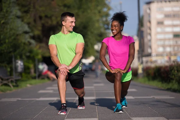 Jogging couple warming up and stretching in the city — Stock Photo, Image