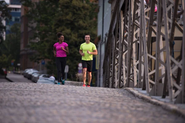 Jonge glimlachend multi-etnisch paar joggen in de stad — Stockfoto