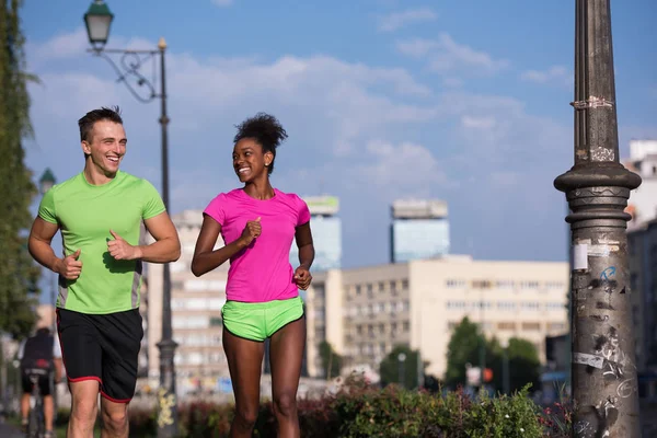 Mladý, usměvavý mnohonárodnostní pár běhání ve městě — Stock fotografie