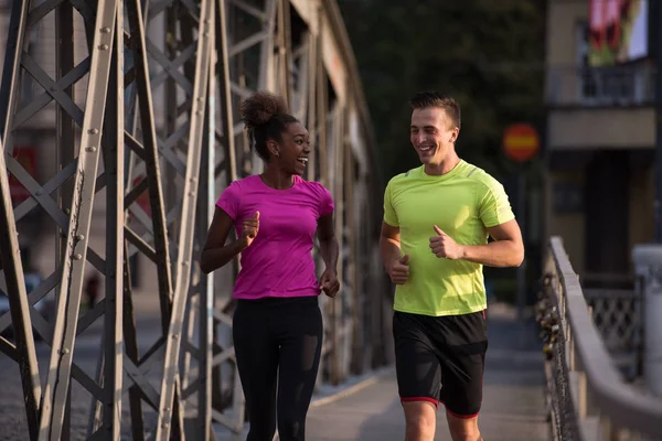 Jonge glimlachend multi-etnisch paar joggen in de stad — Stockfoto