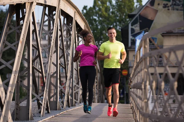 Young smiling multiethnic couple jogging in the city — Stock Photo, Image