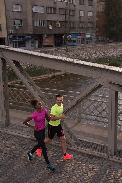 Młode, uśmiechnięte wieloetnicznym para joggingu w mieście — Zdjęcie stockowe