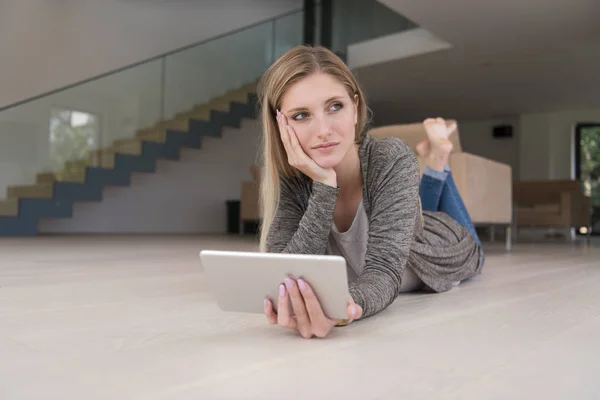 Молодая женщина пользовалась планшетным компьютером на полу — стоковое фото
