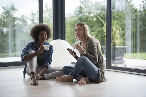Multietniskt kvinnor sitta på golvet och dricka kaffe — Stockfoto