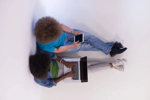多种族的夫妇坐在地板上的一台笔记本电脑和平板电脑 — 图库照片