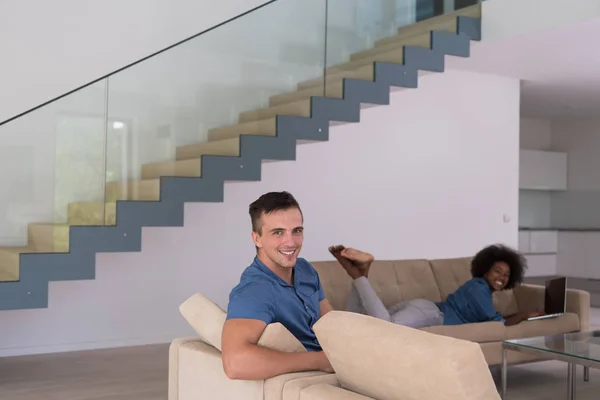 Jovem casal multiétnico relaxa na sala de estar — Fotografia de Stock