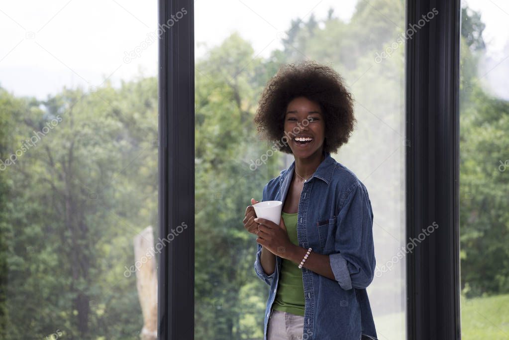 African American woman drinking coffee looking out the window