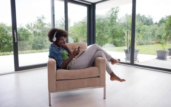 Αφρικανική αμερικανική γυναίκα στο σπίτι σε καρέκλα με tablet — Φωτογραφία Αρχείου