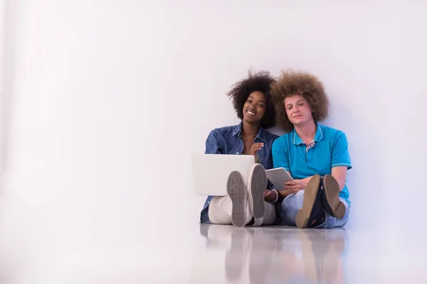 Wieloetniczny para siedzi na podłodze z laptopa i tabletu — Zdjęcie stockowe