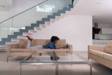 Afrikalı-Amerikalı kadın kanepede dizüstü bilgisayar kullanarak