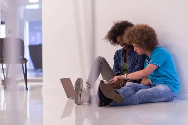 Coppia multietnica seduta sul pavimento con un computer portatile e tablet — Foto Stock