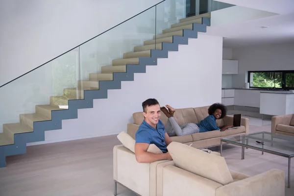 Jovem casal multiétnico relaxa na sala de estar — Fotografia de Stock