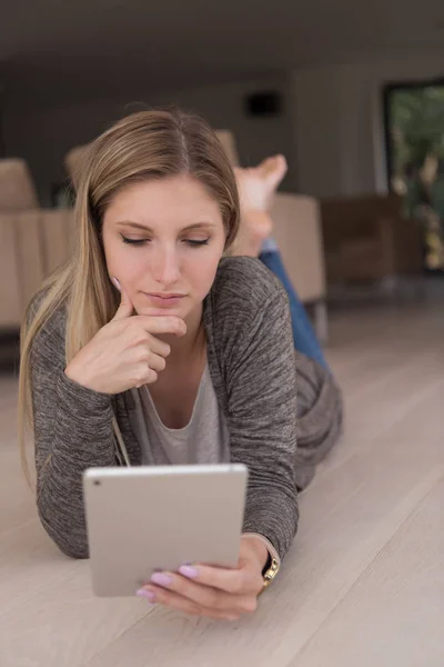 Mujer joven utiliza tableta ordenador en el suelo — Foto de Stock