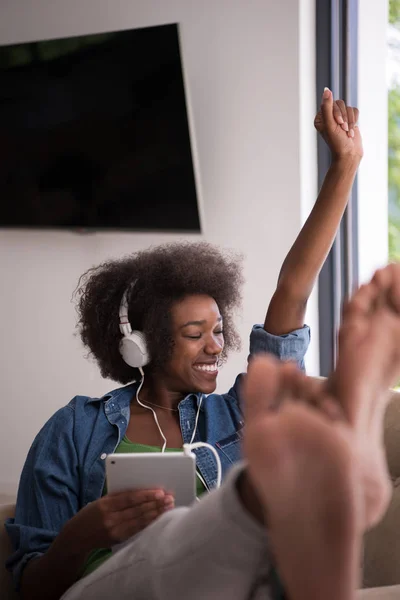 Africano americano mulher em casa na cadeira com tablet e cabeça pho — Fotografia de Stock