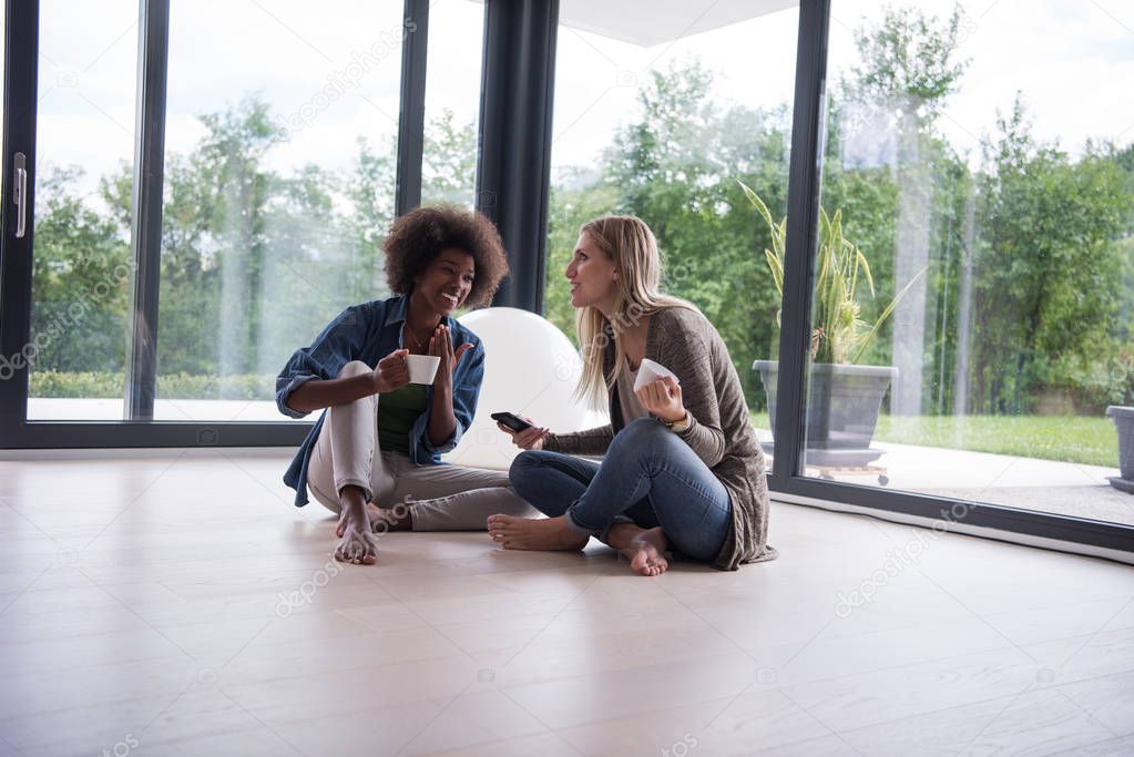 multiethnic women sit on the floor and drinking coffee
