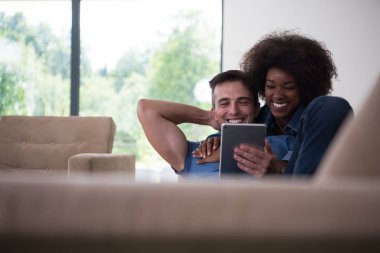 çok ırklı çift evde tablet bilgisayarlar ile rahatlatıcı