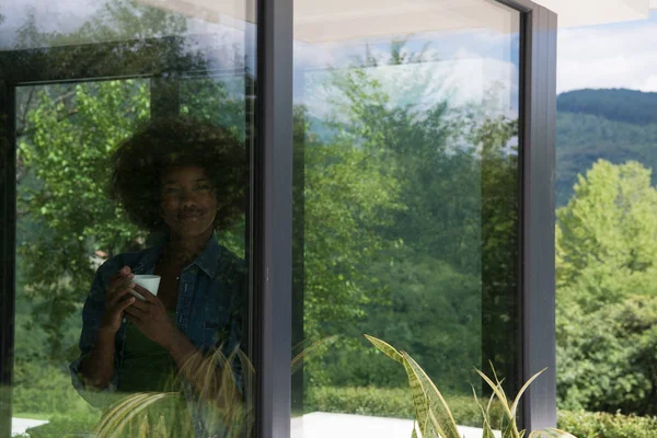 African American woman drinking coffee looking out the window — Stock Photo, Image