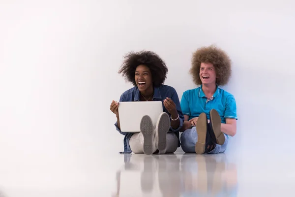 Casal multiétnico sentado no chão com um laptop e tablet — Fotografia de Stock