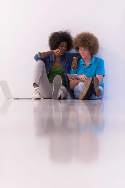 Couple multiethnique assis sur le sol avec un ordinateur portable et tablette — Photo