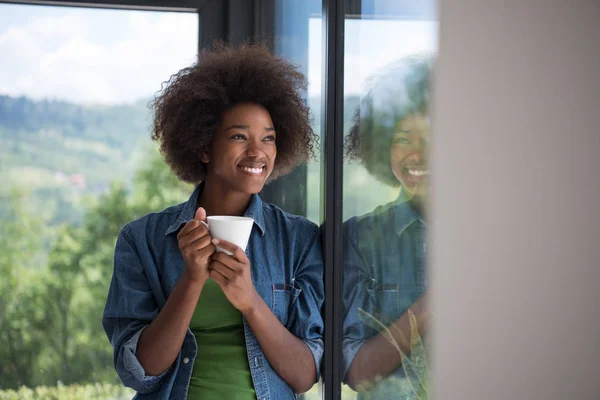 Femme afro-américaine boire du café regardant par la fenêtre — Photo