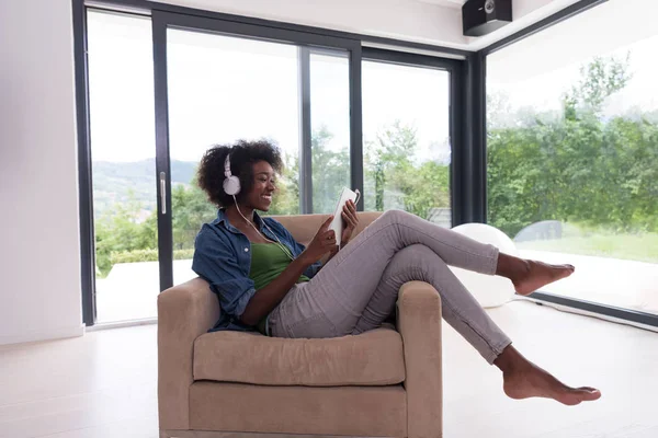 Mujer afroamericana en casa en silla con tablet —  Fotos de Stock