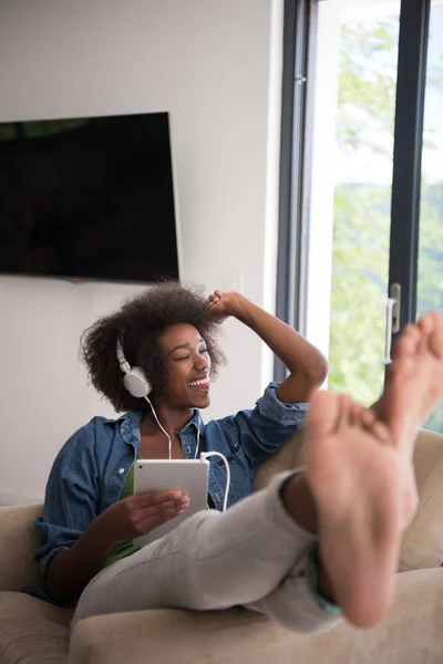 Femme afro-américaine à la maison dans une chaise avec tablette — Photo