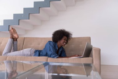 Afrikalı-Amerikalı kadın kanepede dizüstü bilgisayar kullanarak