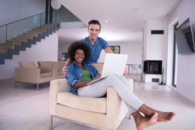 çok ırklı çift bir dizüstü bilgisayar ile bir koltuk üzerinde