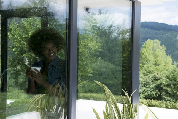 Mujer afroamericana bebiendo café mirando por la ventana — Foto de Stock