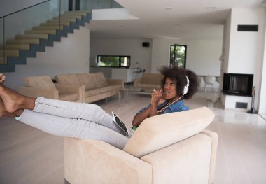 Afrikalı-Amerikalı kadın evde tablet ve kafa pho ile sandalyede