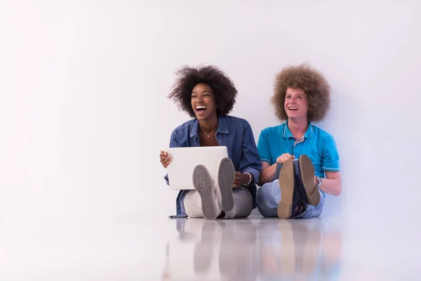 Mnohonárodnostní pár sedí na podlaze s notebooku a tabletu — Stock fotografie