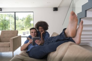 çok ırklı çift evde tablet bilgisayarlar ile rahatlatıcı