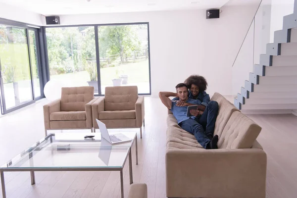 Unga multietniskt par slappnar av i vardagsrummet — Stockfoto