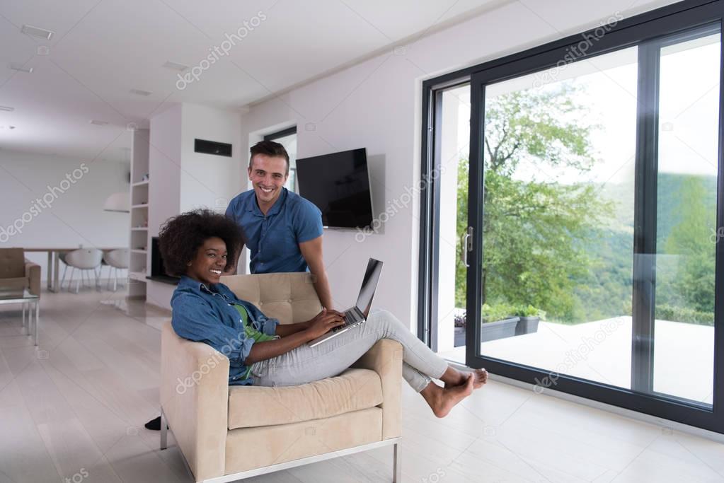 multiethnic couple on an armchair with a laptop