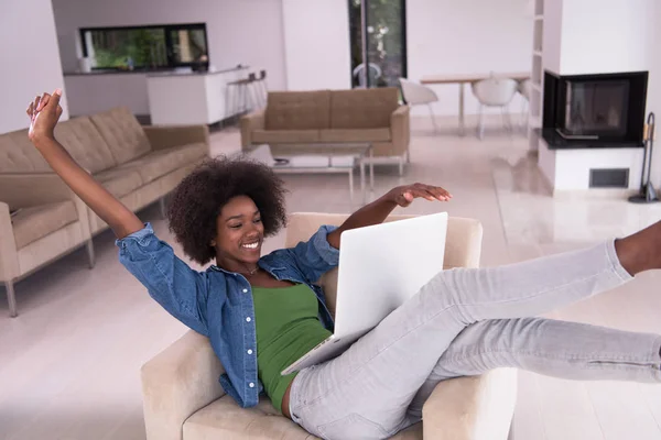 Mujer afroamericana en casa en la silla usando una computadora portátil —  Fotos de Stock