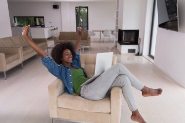 Bir dizüstü bilgisayar kullanarak sandalyede Afrikalı-Amerikalı kadınlar evde