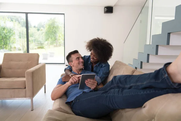 Casal multiétnico relaxante em casa com computadores tablet — Fotografia de Stock