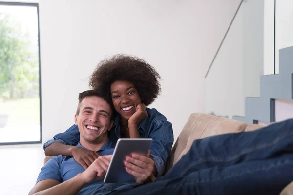 Casal multiétnico relaxante em casa com computadores tablet — Fotografia de Stock