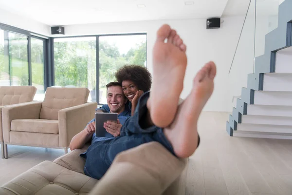 Casal multiétnico relaxante em casa com computadores tablet — Fotografia de Stock