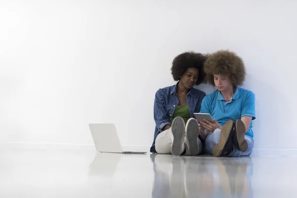 Couple multiethnique assis sur le sol avec un ordinateur portable et tablette — Photo