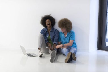 çok ırklı çift bir dizüstü ve tablet ile katta oturan