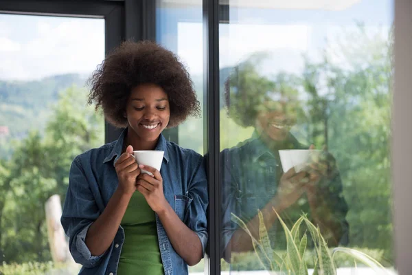 African American vrouw drinken koffie kijkt uit het raam — Stockfoto