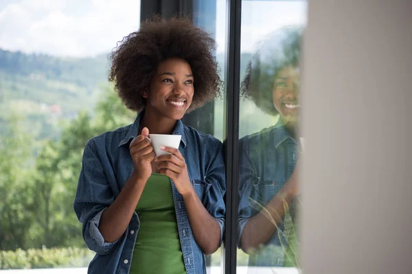 African American vrouw drinken koffie kijkt uit het raam — Stockfoto