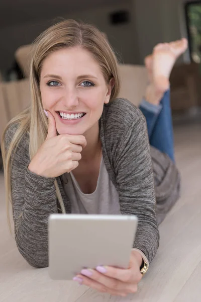 Mujer joven utiliza tableta ordenador en el suelo — Foto de Stock
